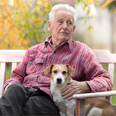 elderly man sitting on an outdoor bench with a small dog