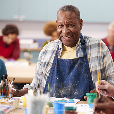 elderly male resident smiling while painting