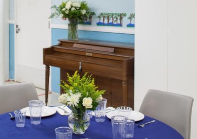 Dining room table set with bright blue tablecloths and fresh flowers